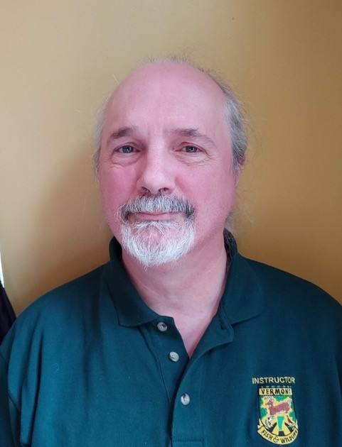 white male, grey beard and mustache blue shirt slight smile