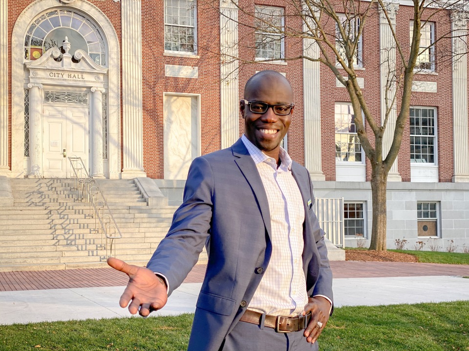 Man with hand held out in front of a building