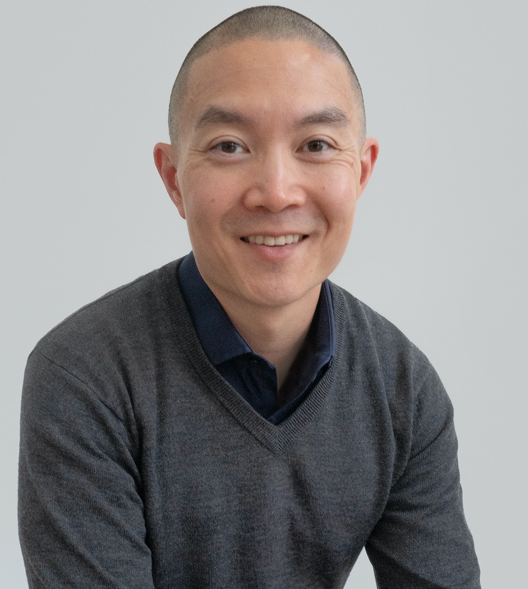 man, short cropped hair, grey v-neck sweater, smile