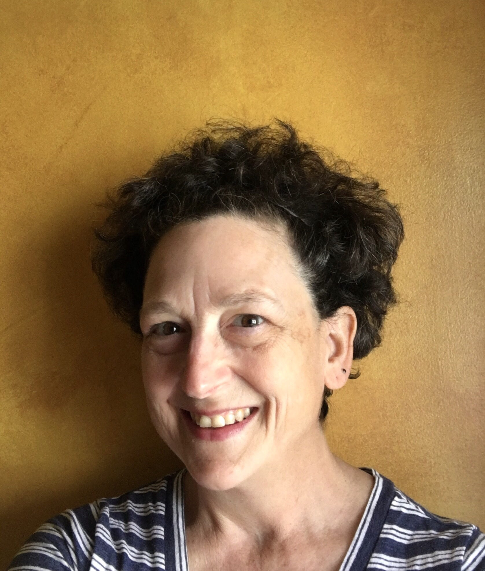 White woman with short brown hair, blue shirt, big smile