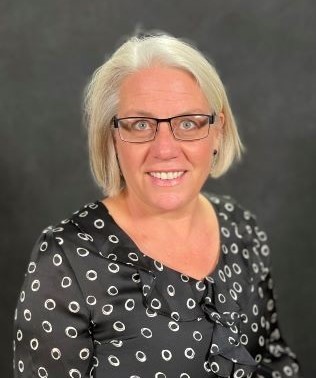 Female in black printed top, very blond hair, dark glasses