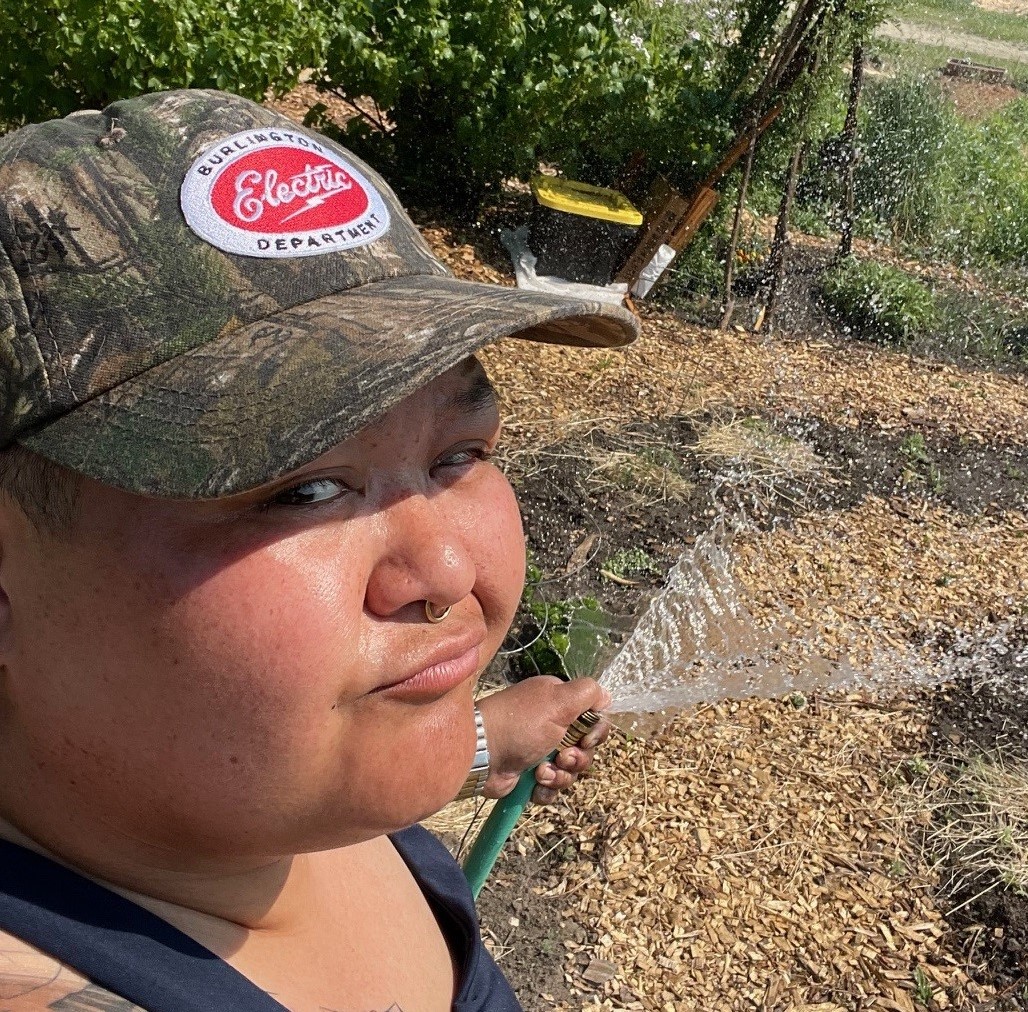 person with a wink, holding a hose and spraying crops